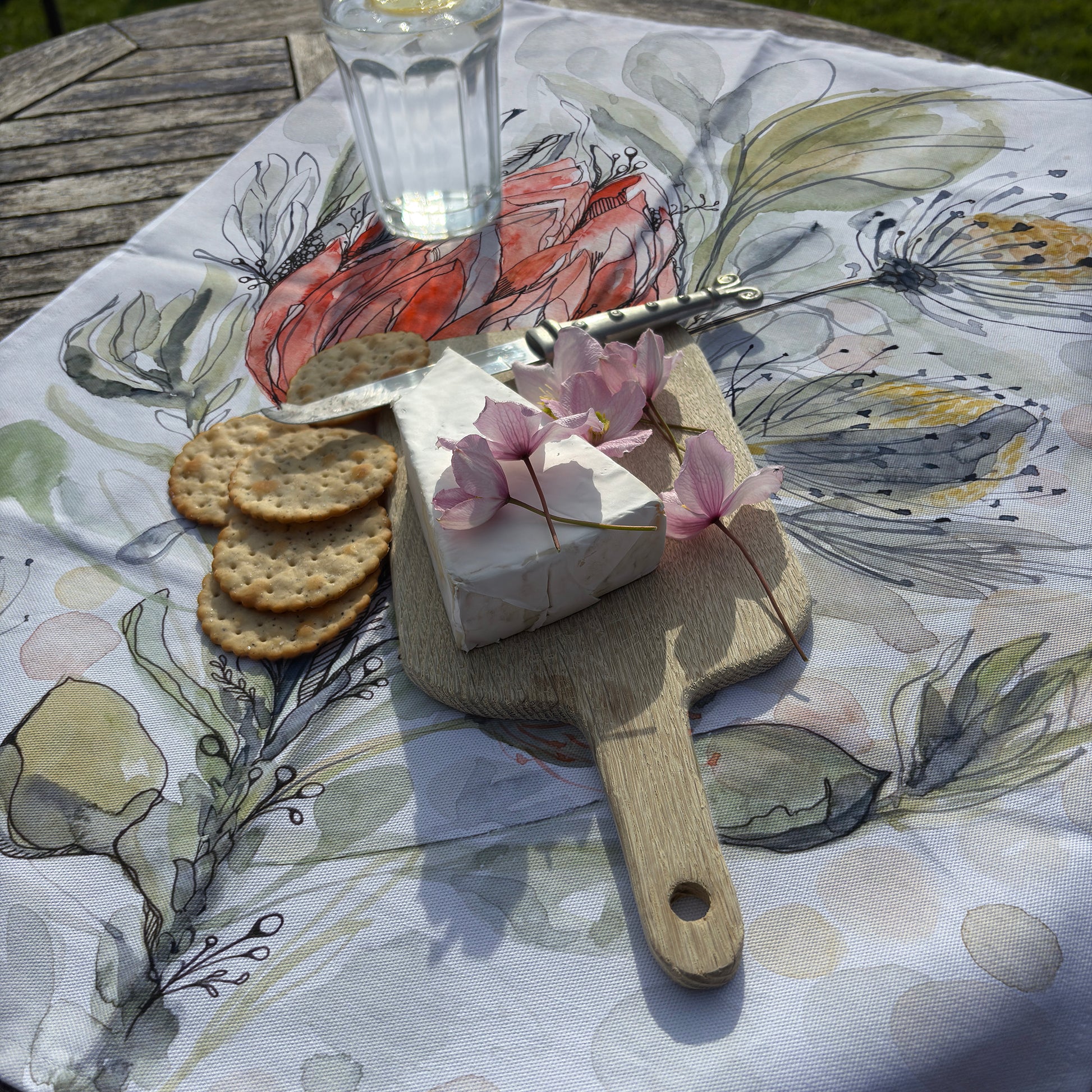 Cheeseboard with crackers and flowers on a TranquilHive Tea Towel - Coral Protea