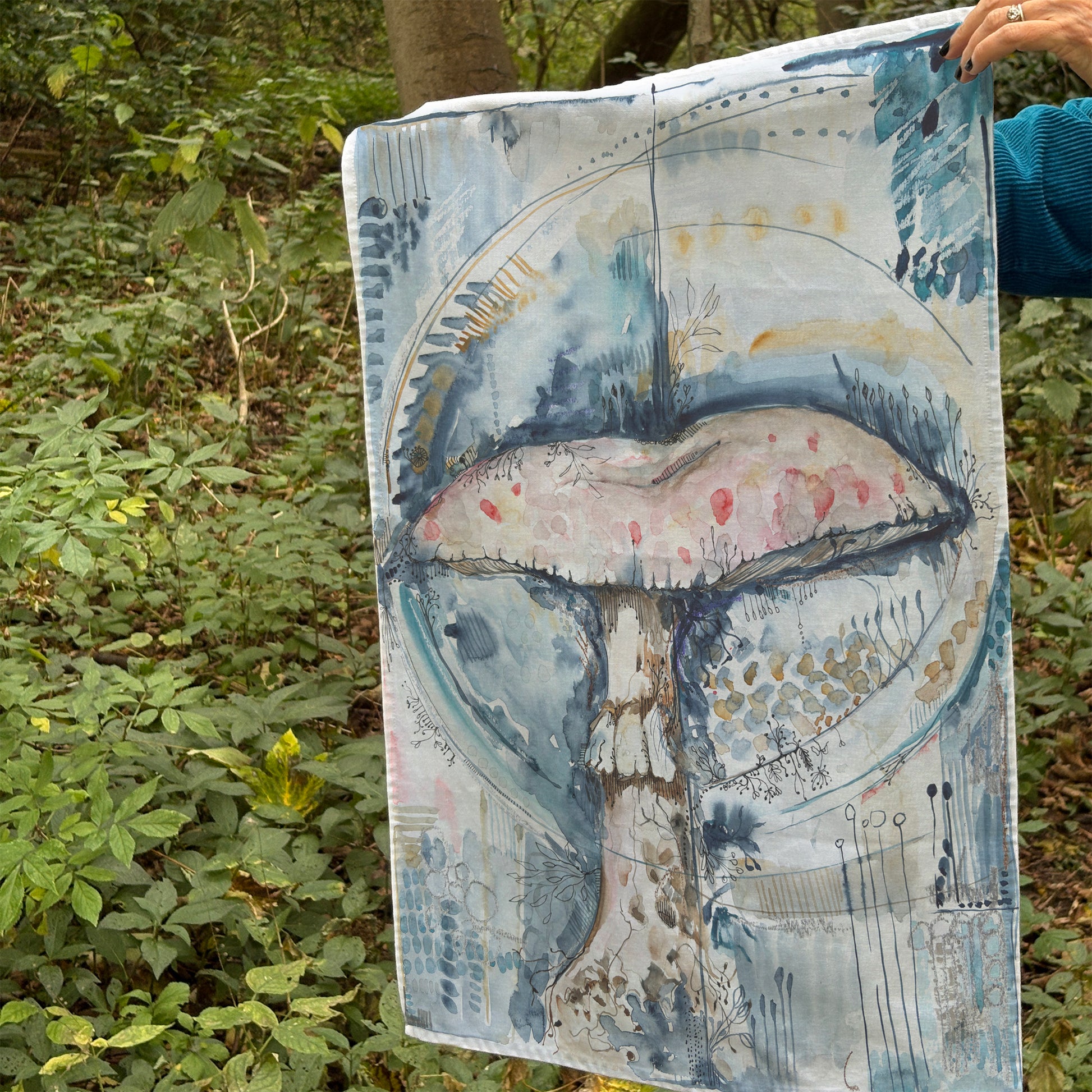 Painting of a mushroom tea towel held by Bonny Jennings in a forest setting