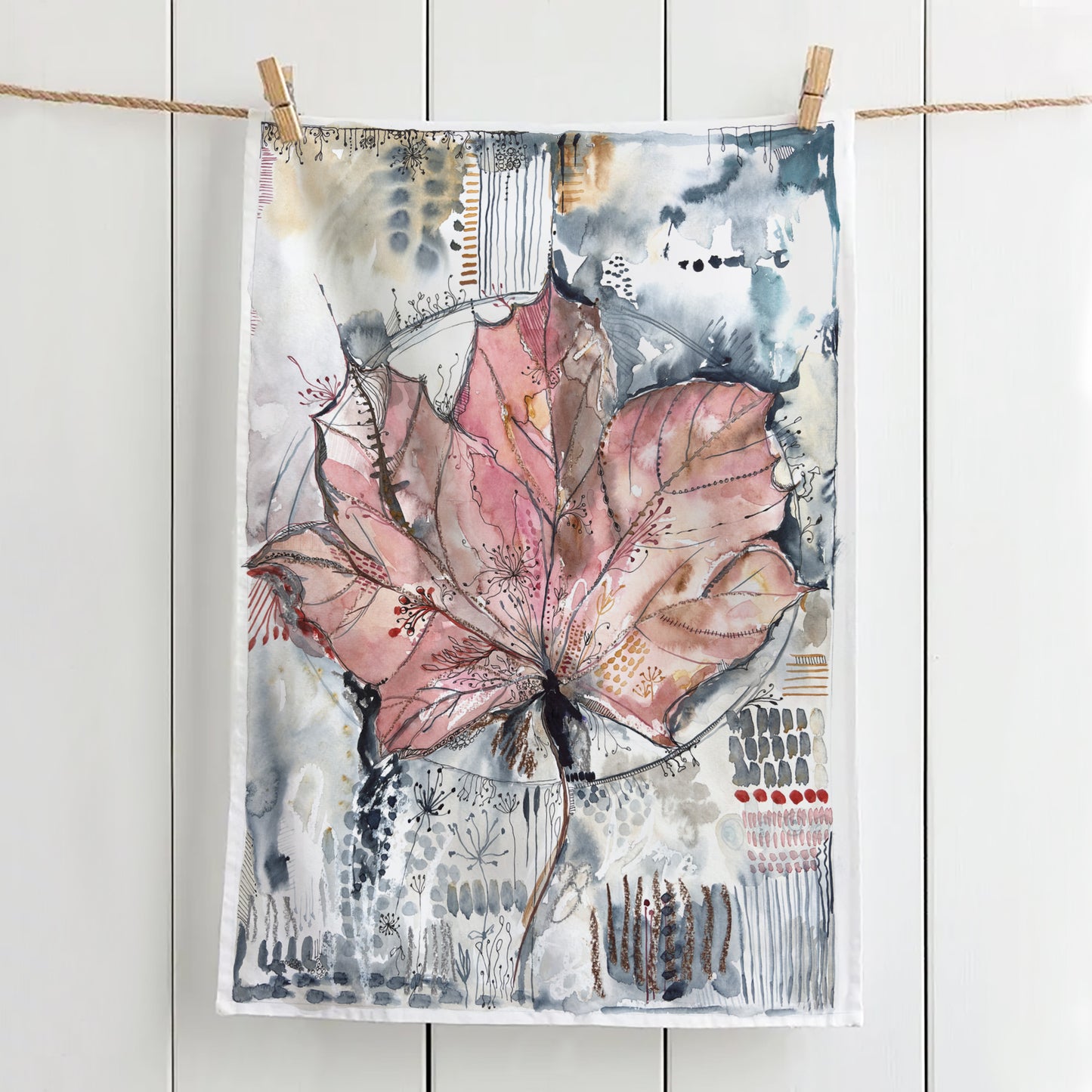 Tea towel with a maximalist maple leaf design hanging with clothes pegs on a line