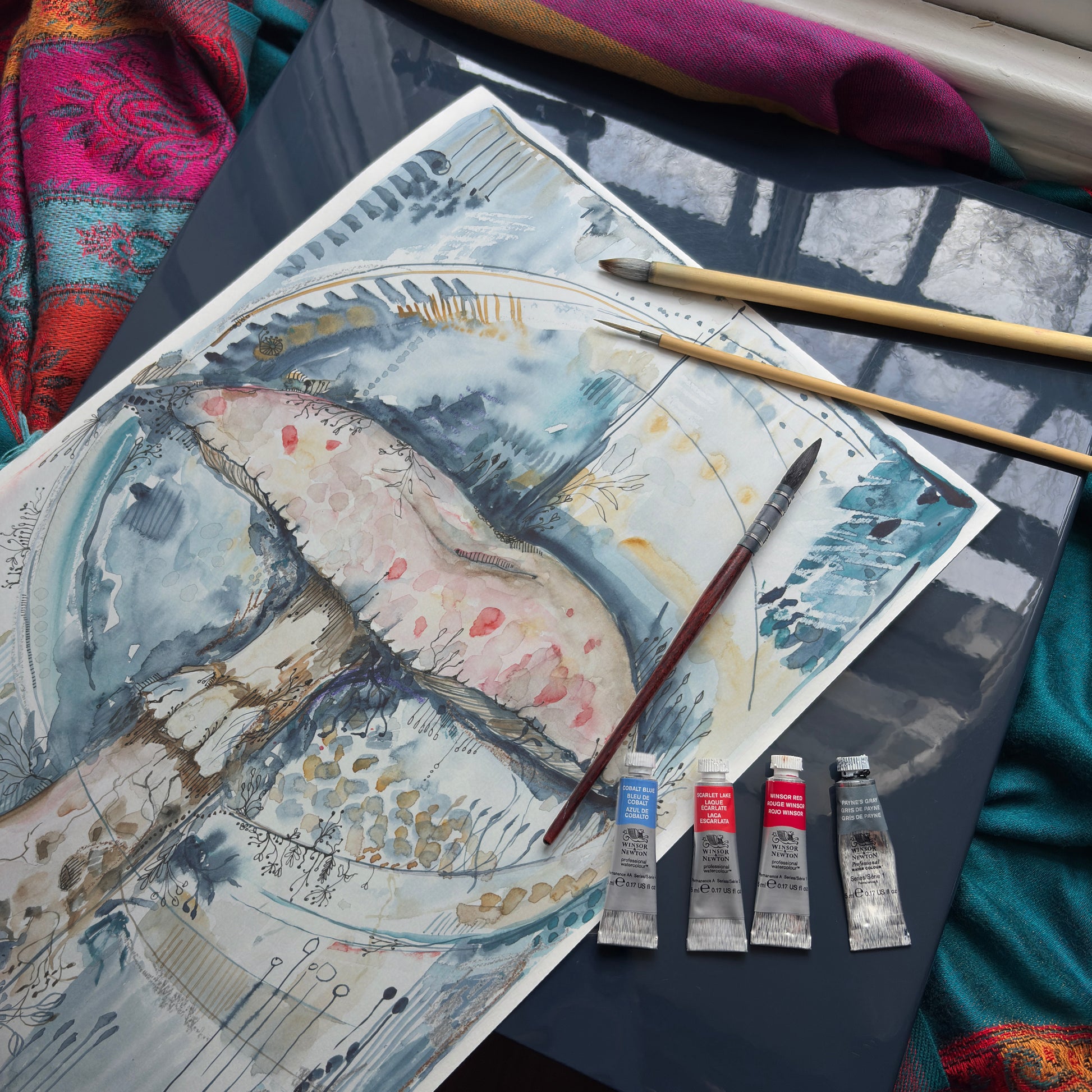 painting mushroom for tea towel with paint tubes, paintbrushes and sun coming in the window