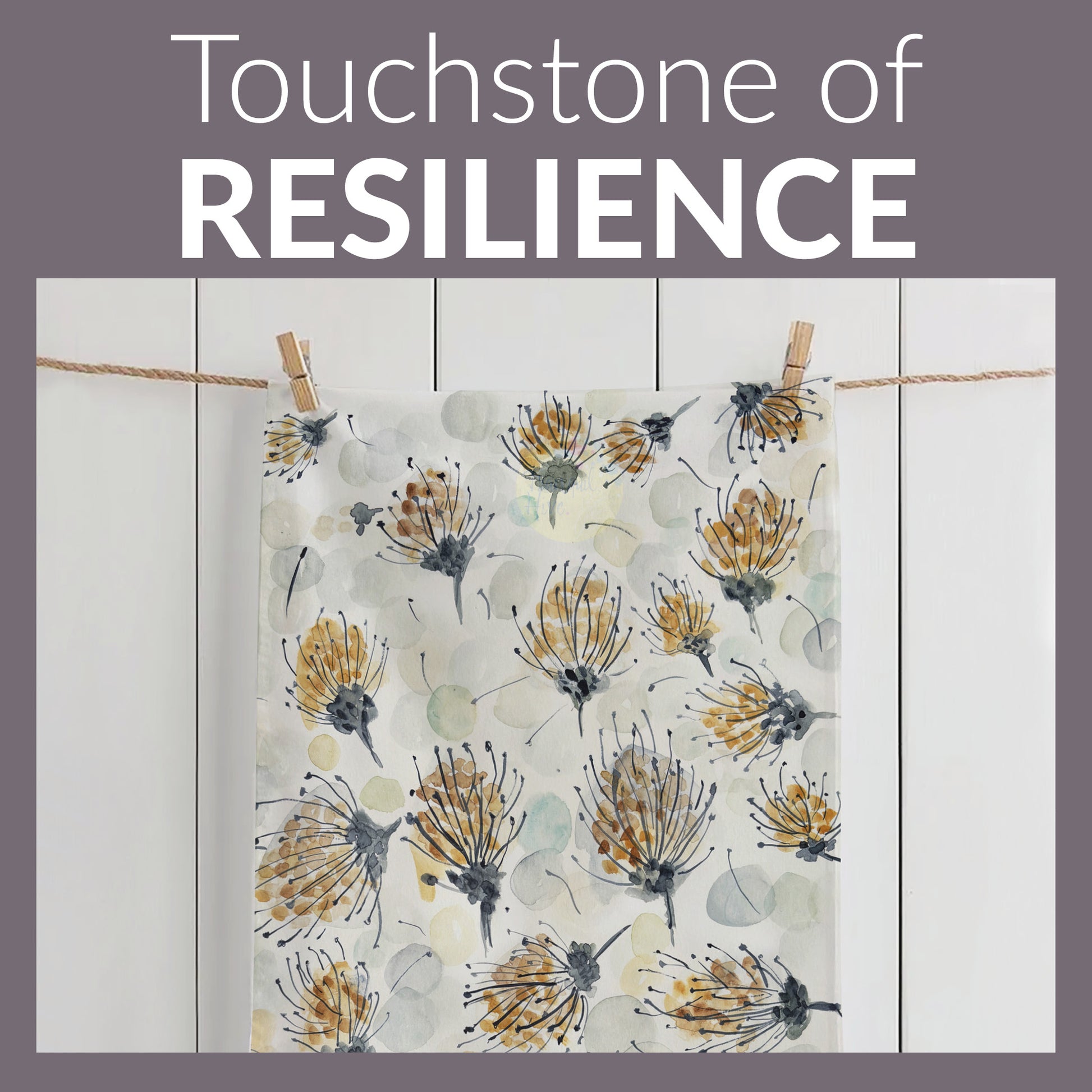 A tea towel with a watercolor-style botanical design featuring delicate pin cushion protea in shades of gold, gray, and black, along with soft, abstract circular shapes in muted tones. The towel is hanging on a line