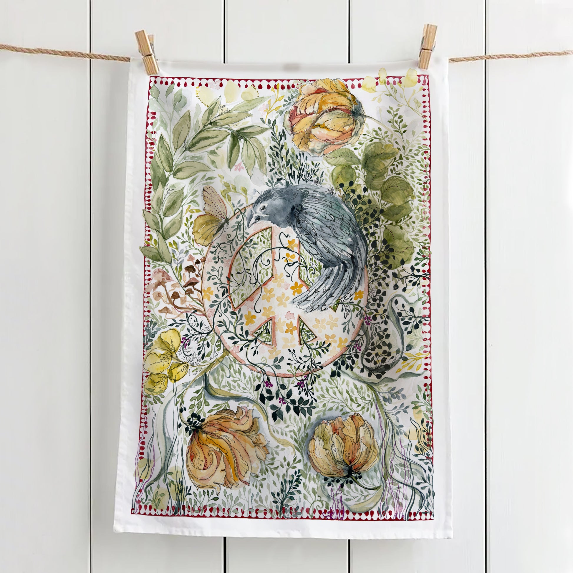 Tea towel with crow watching over a peace sign hanging on a line with pegs